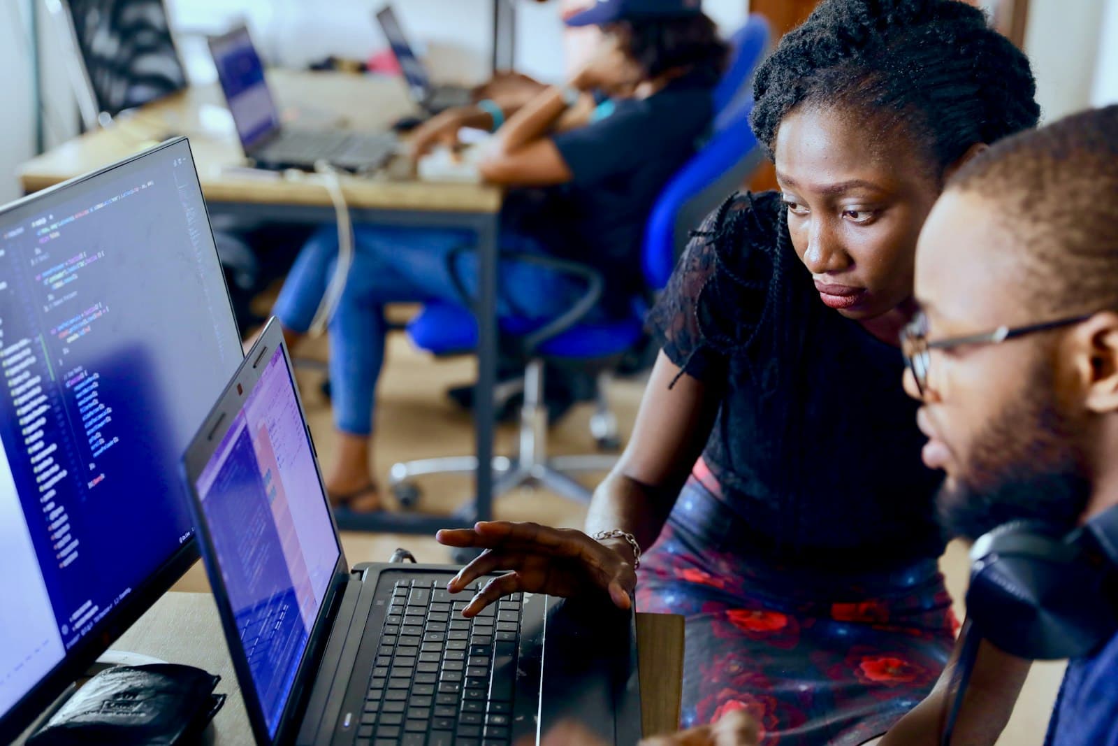 Two young developers reviewing code together at a shared workspace